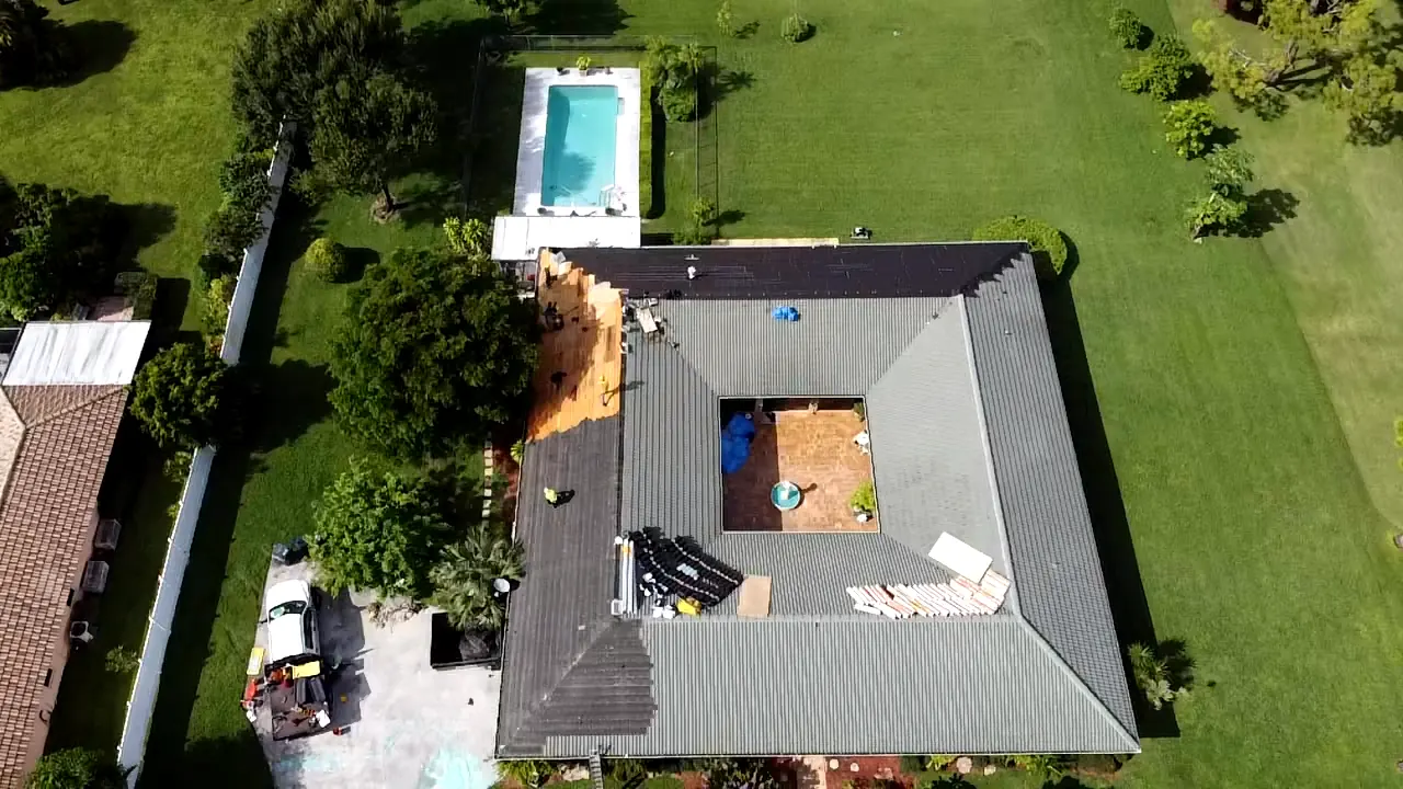 Aerial view of a gray metal reroof while panels are being installed