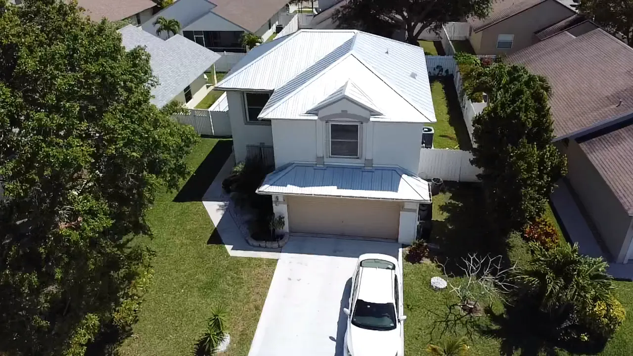 Front aerial view of a two-story home with a white metal roof