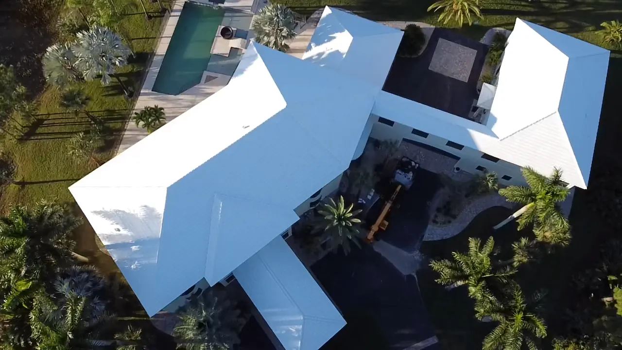 Aerial view of a large home with a completed white metal roof
