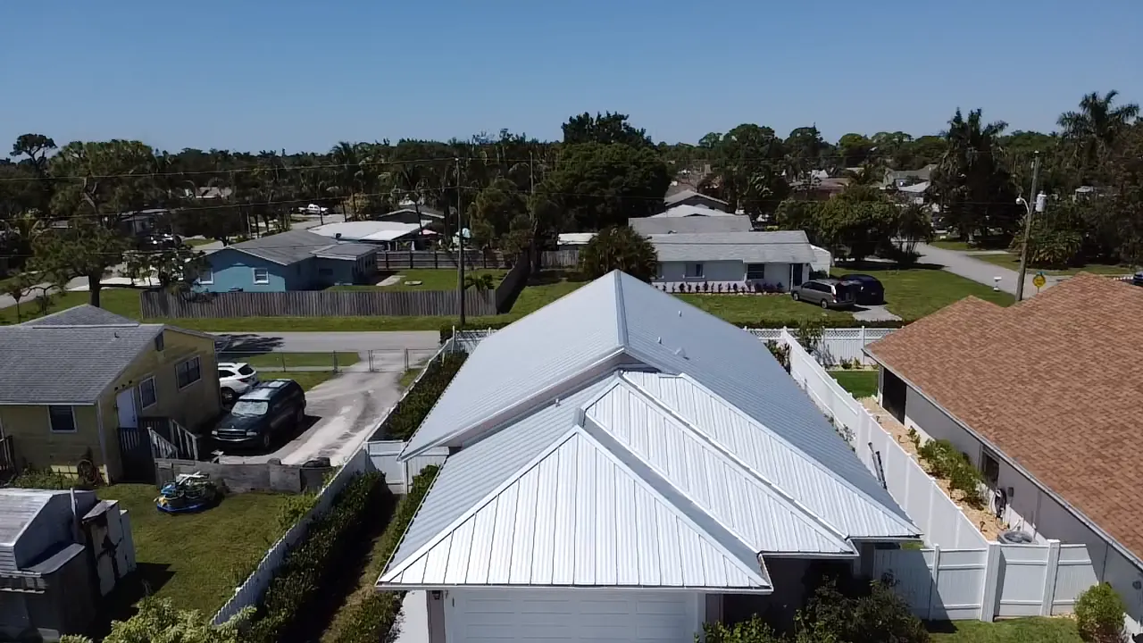 Rear aerial view of a compact home with a white metal roof