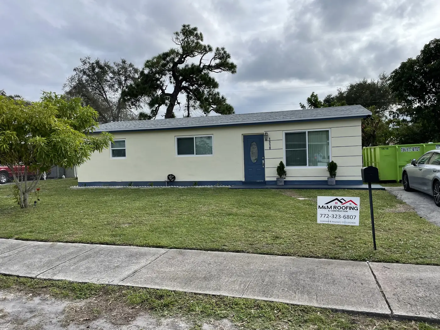 Home with a completed white metal roof and an M&M Roofing project sign