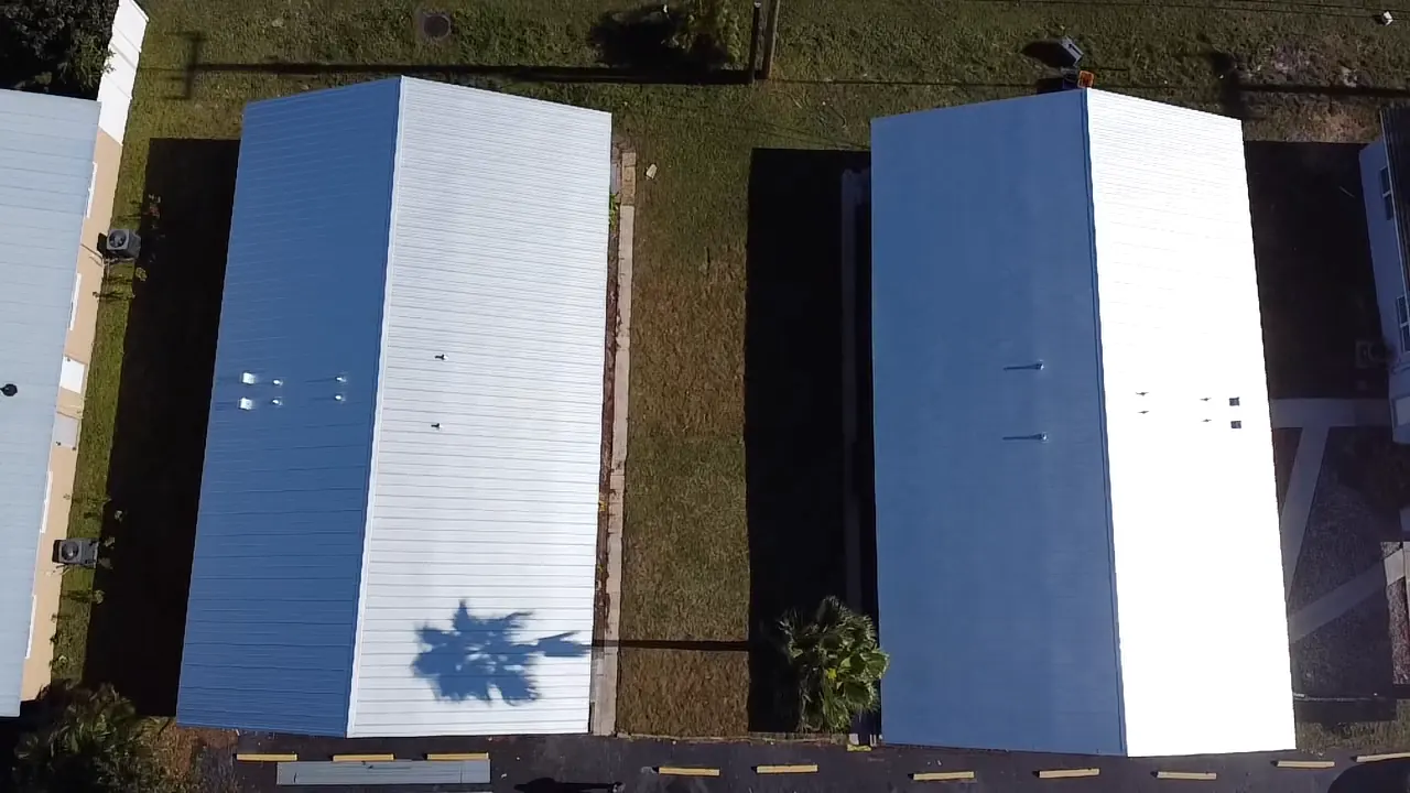 Top-down view of white metal roofs on two neighboring buildings